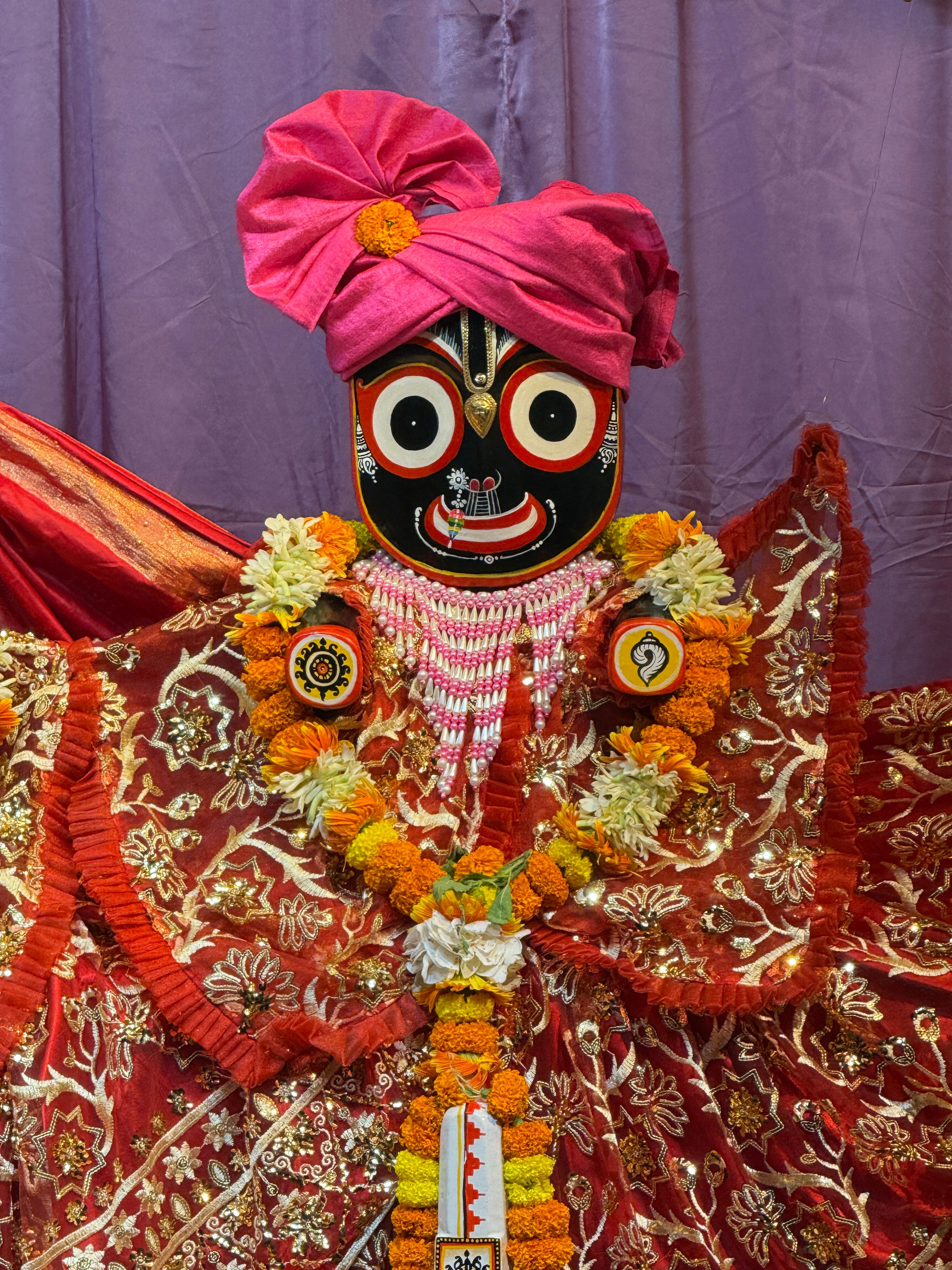 Colorful Jagannath idol adorned in intricate attire and floral garlands.