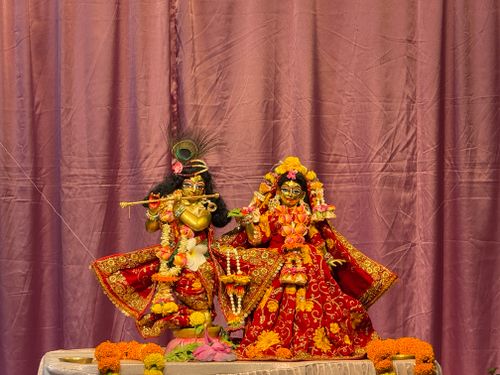 Free Vibrant statues of Krishna and Radha in colorful attire with decorative floral elements indoors. Stock Photo