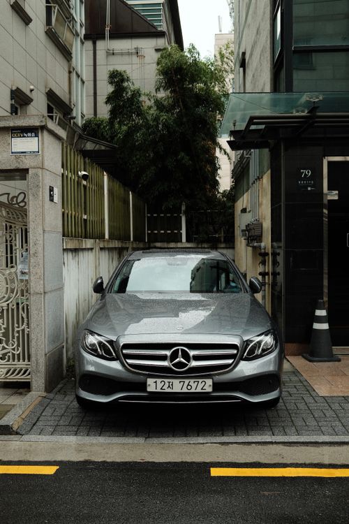Free A sleek gray luxury car parked in a narrow urban alley, exemplifying modern city life. Stock Photo
