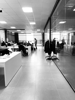 Black and white of anonymous employees working together in modern office with glass walls