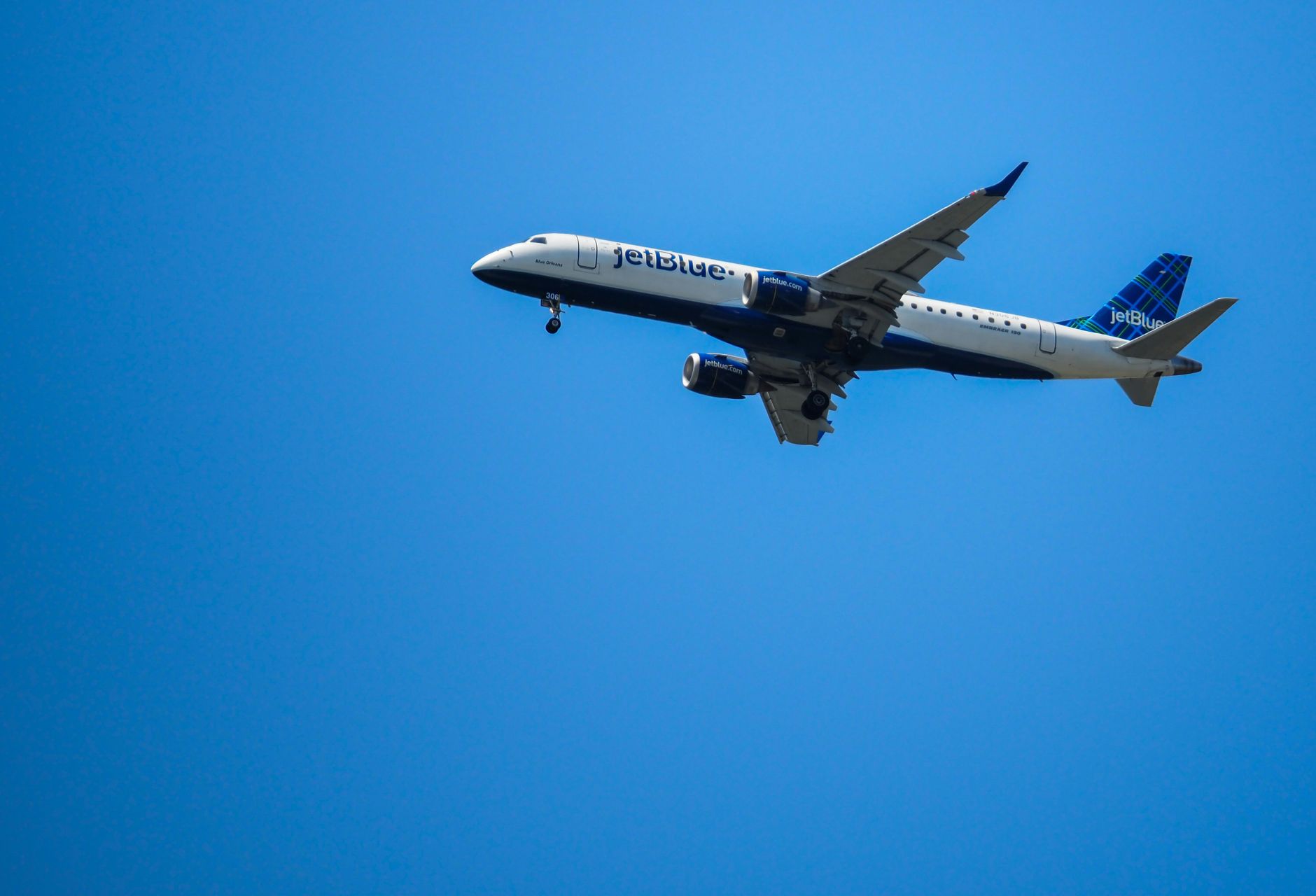 JetBlue airplane flying in clear blue skies, showcasing aviation in motion.