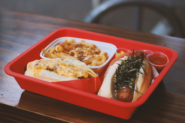Authentic Vancouver Japadog and poutine served in a vibrant red tray, showcasing Japanese-Canadian fusion cuisine.