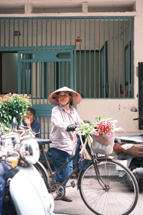 Free A woman street vendor on bicycle carrying colorful flowers in Jaipur, India. Stock Photo