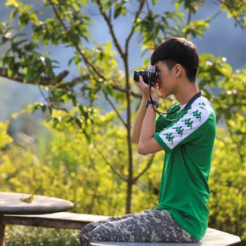 Young man in Lào Cai, Vietnam, capturing nature with a camera outdoors.