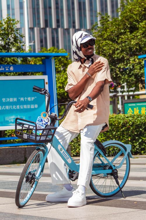 Free Casual cyclist resting on bike in bright urban street, enjoying a sunny day. Stock Photo