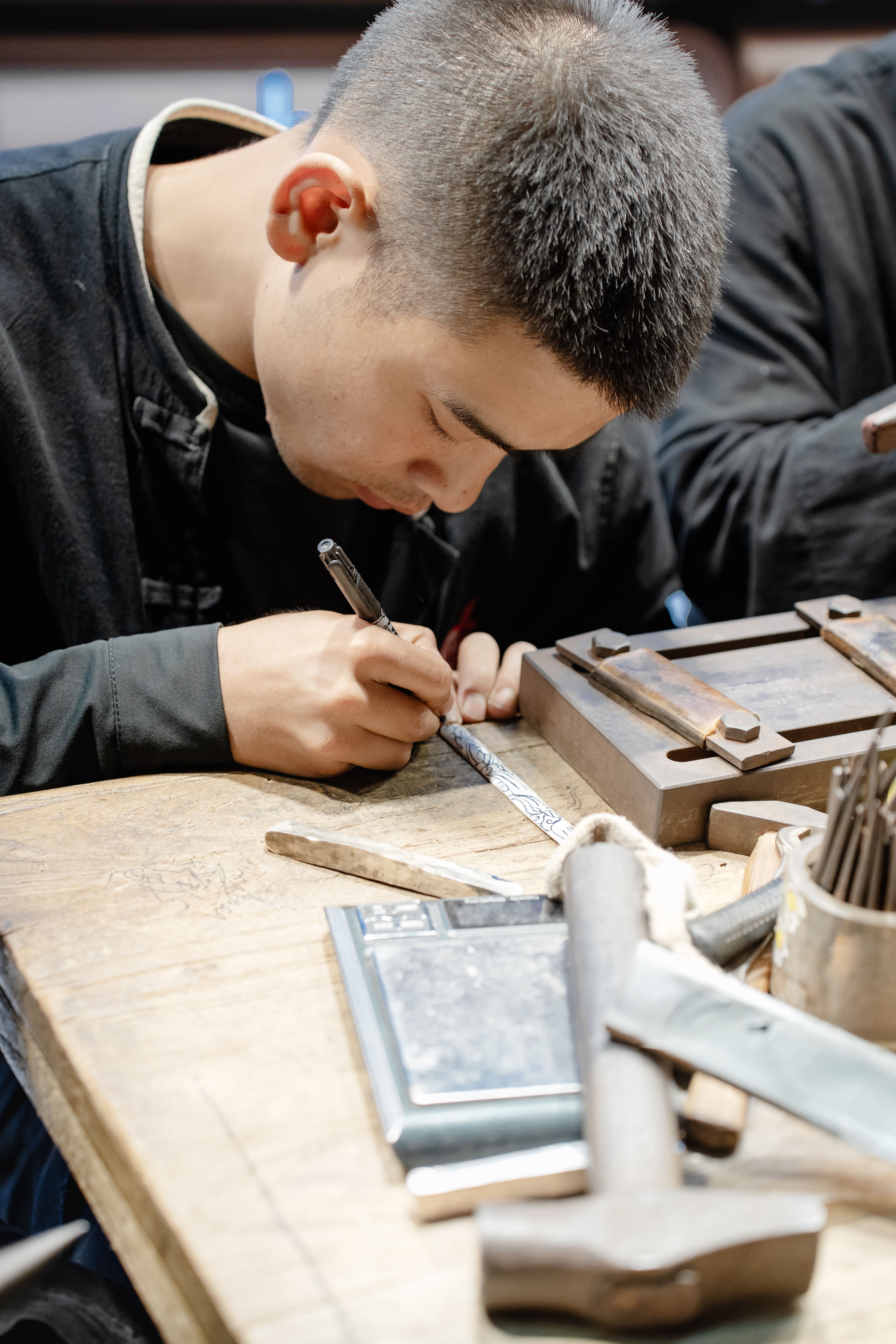 Focused craftsman engraving intricate designs on wood table in workshop.