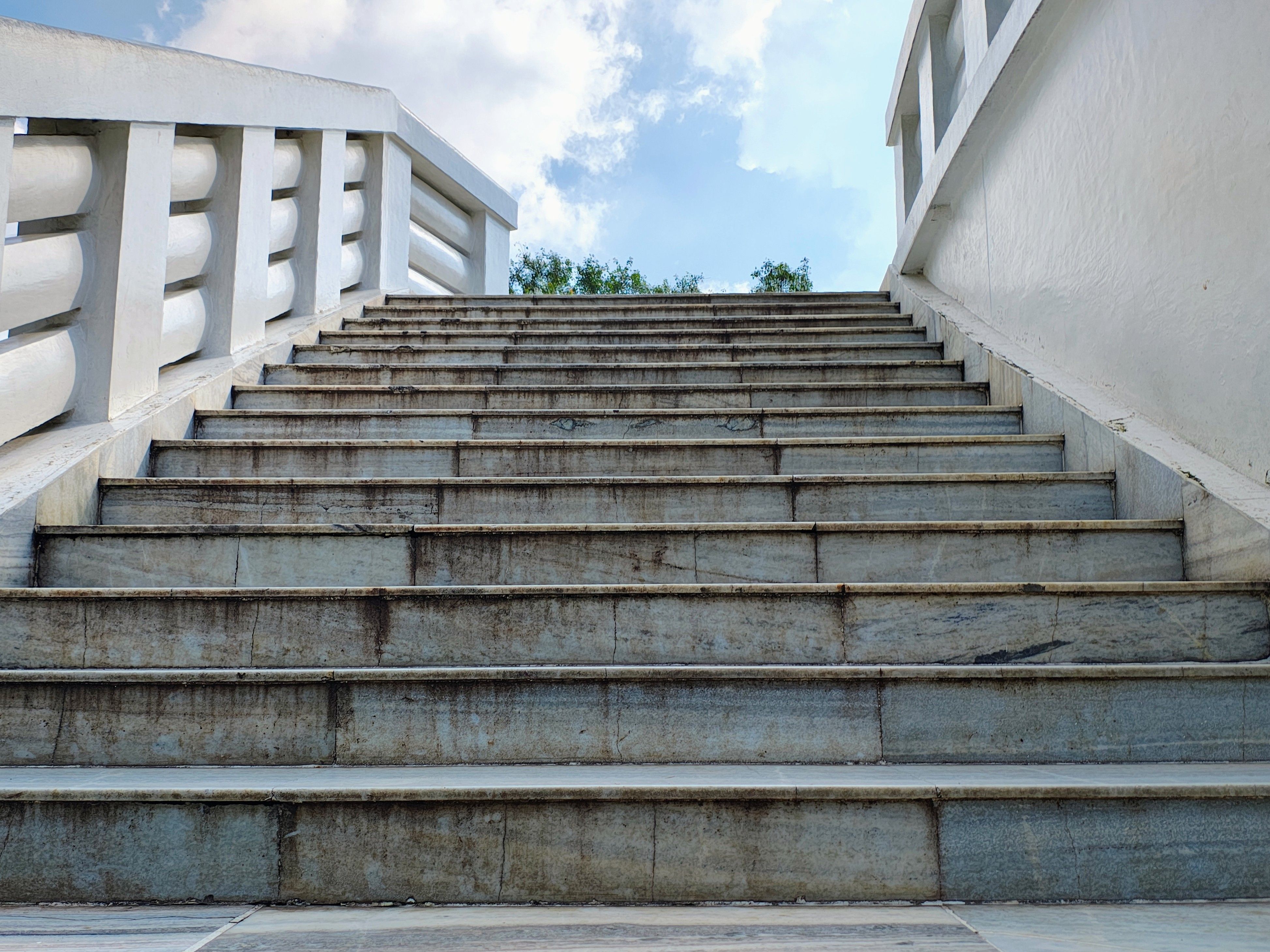 Perspective shot of an outdoor concrete staircase leading up to the sky with white railing.