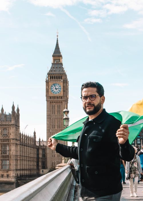 Free Man with flag poses in front of the iconic Big Ben in London, perfect for travel themes. Stock Photo