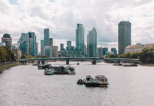 Free Stunning view of London's skyline with the Thames River and iconic skyscrapers under cloudy skies. Stock Photo