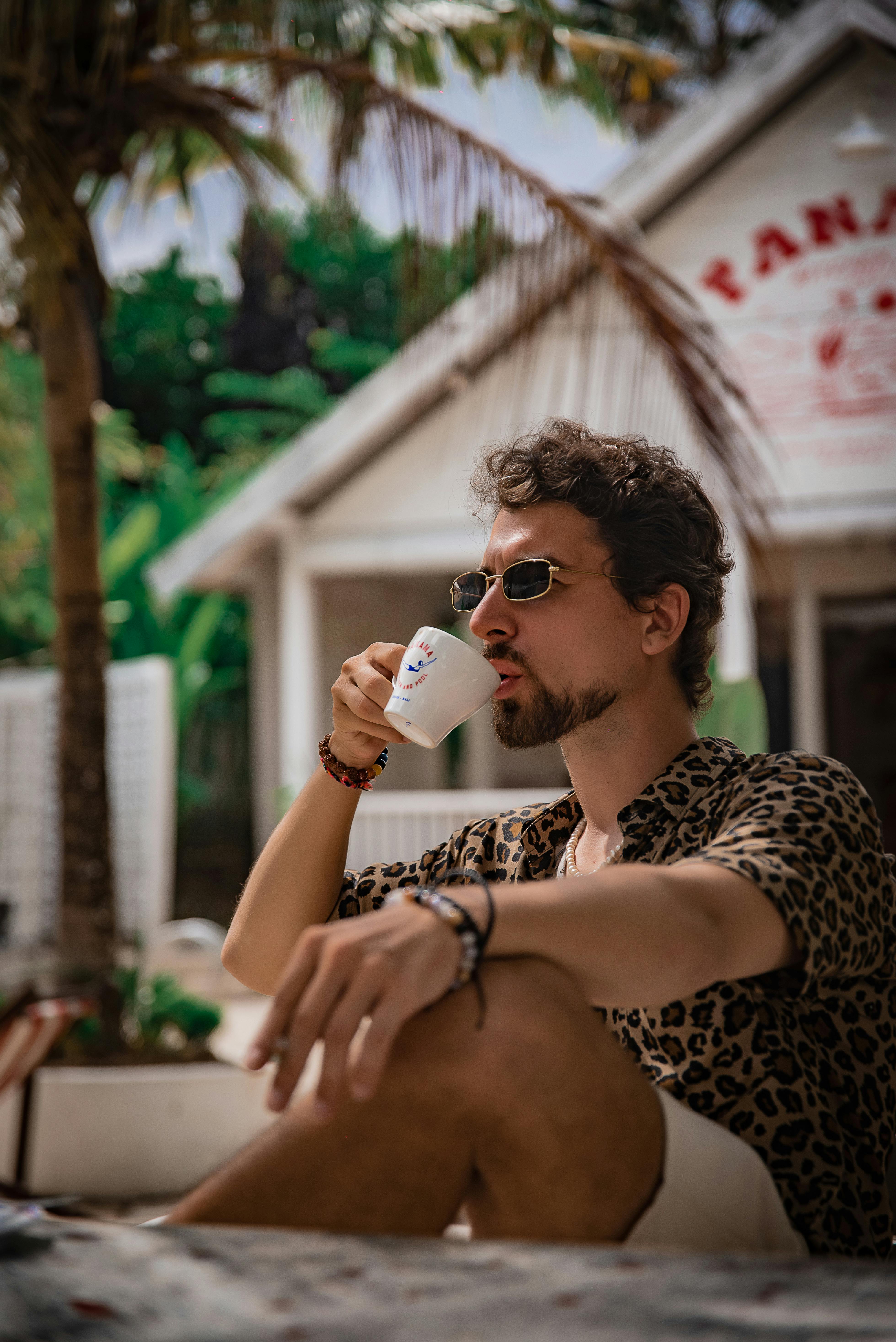 Free A stylish man enjoys coffee at an outdoor café in Bali, Indonesia, exuding tropical vibes. Stock Photo