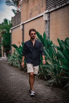 Man walking along a lush tropical street in Bali, Indonesia. Perfect for travel and lifestyle themes.
