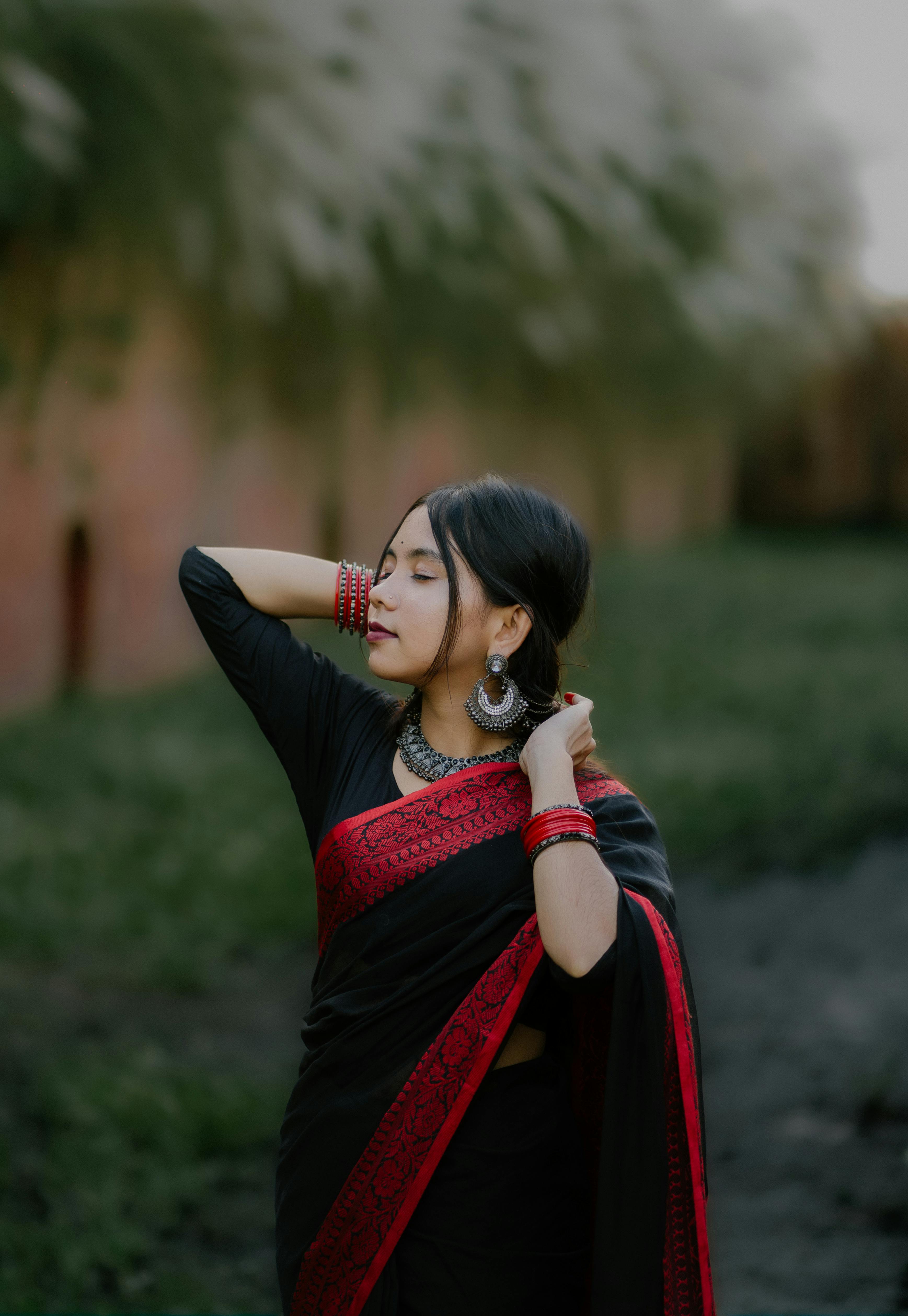 身着红色黑色纱丽的优雅女子在户外展示传统珠宝