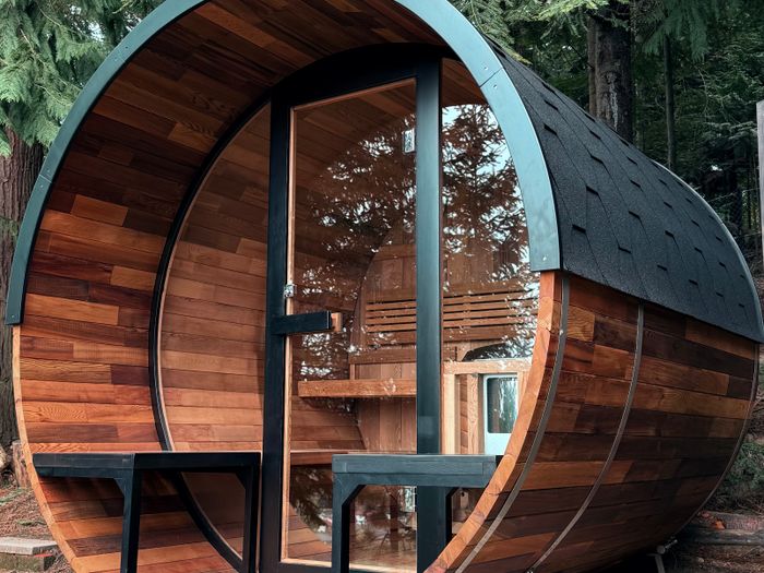 A timber barrel sauna with a glass front