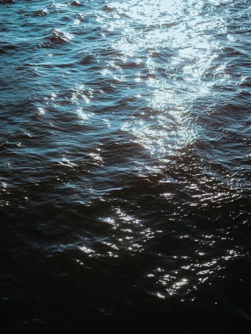 Free Shimmering sunlight reflecting on ocean waves, creating a bright, dynamic pattern. Stock Photo
