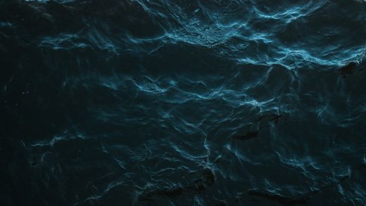 Dark ocean surface with faint light on the swell — photo by Kris Moklebust on Pexels