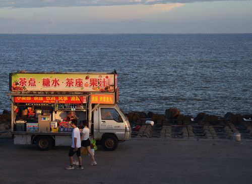Free A seaside snack van with people walking by during sunset. Stock Photo