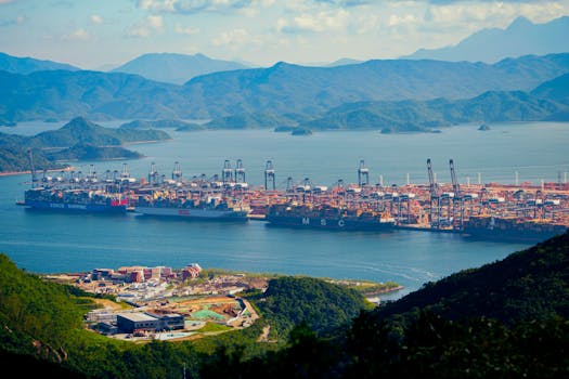 Aerial shot of a bustling shipping port amidst mountains by the water, showcasing international trade.