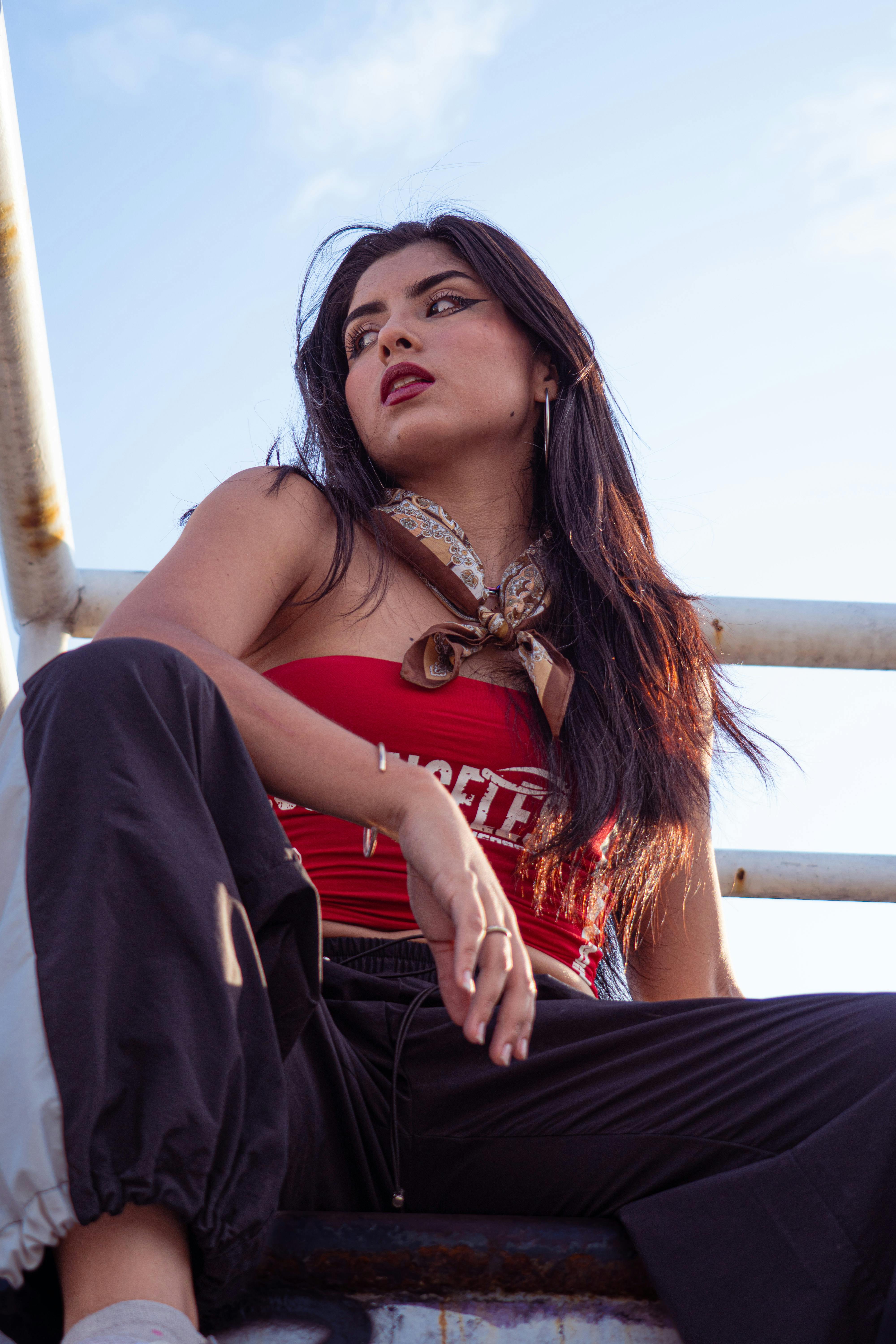 grátis Jovem mulher confiante em roupa da moda posando contra o céu azul. Foto profissional