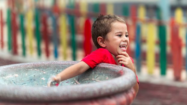 Happy child in a red shirt enjoying a playful moment at an outdoor water park.