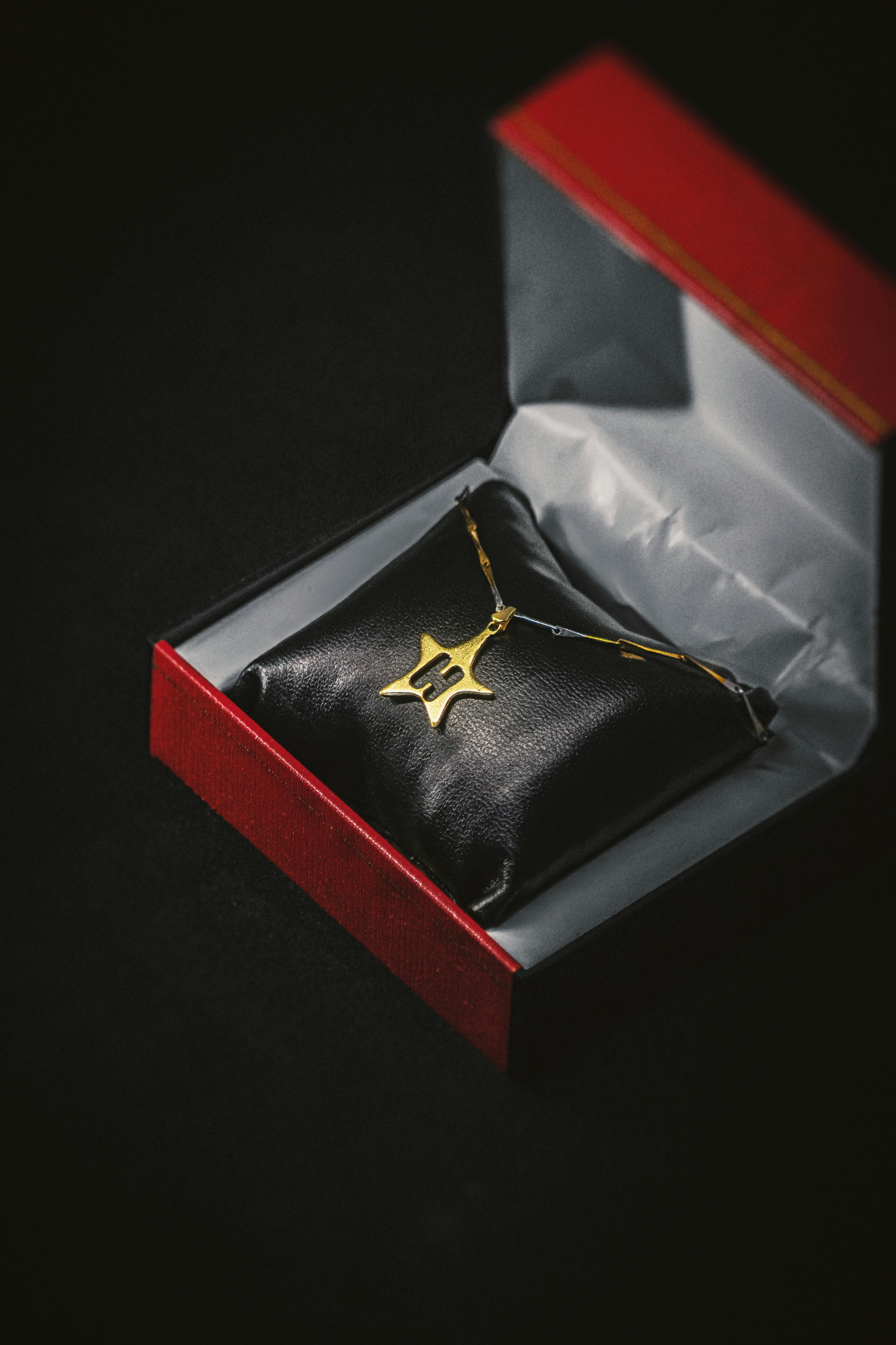 A stylish gold pendant displayed in a luxurious red gift box, exuding timeless sophistication.