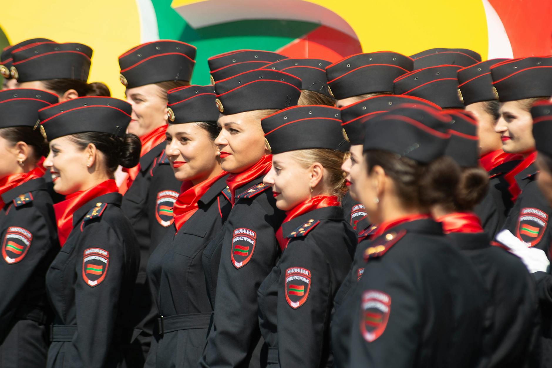Group of female cadets in formal uniforms participating in an outdoor ceremony on a sunny day.
