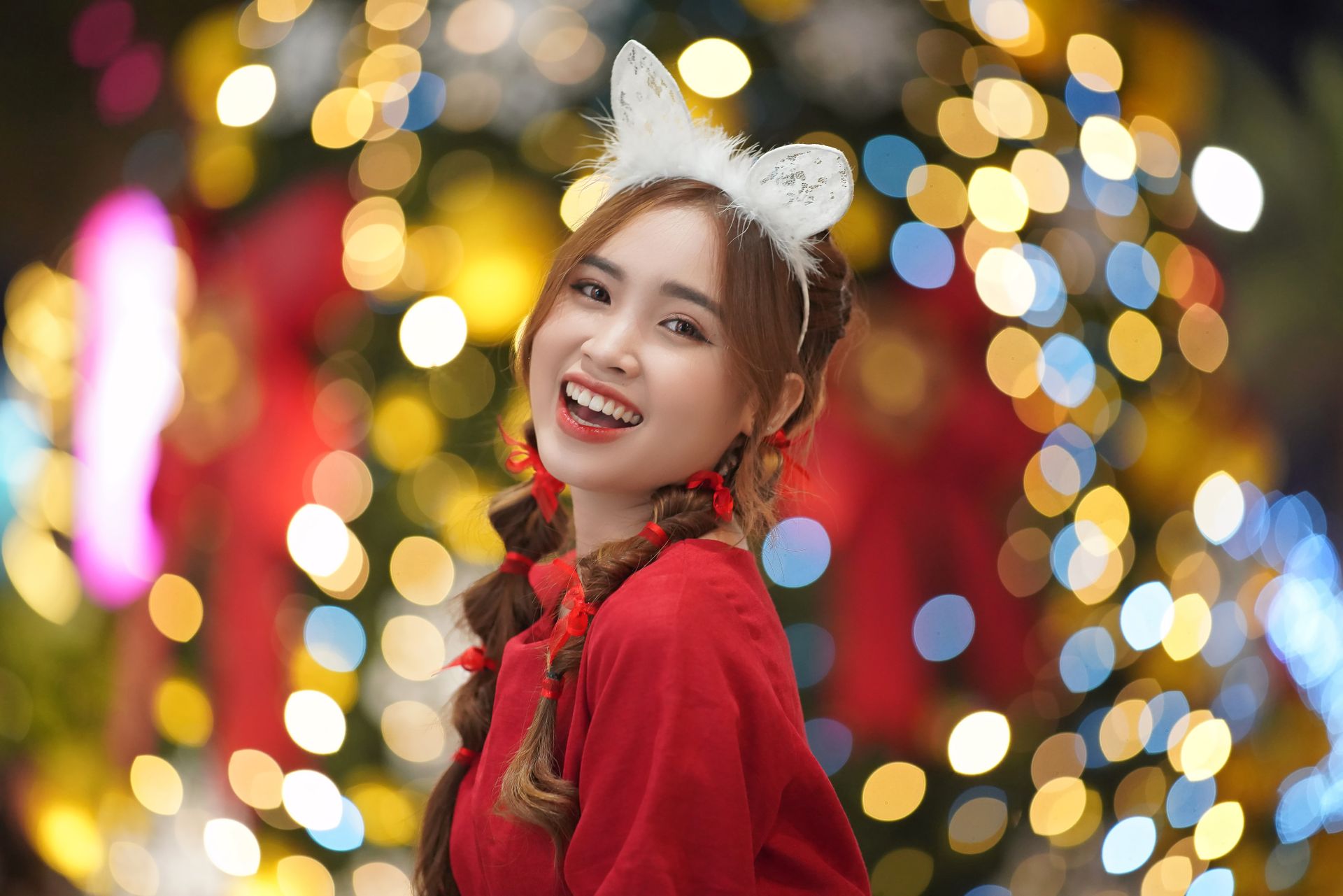 Cheerful woman wearing festive attire with a bokeh background, embodying holiday spirit.