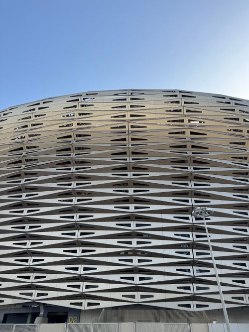 Free Geometric facade detail of a modern building with a clear blue sky background. Stock Photo