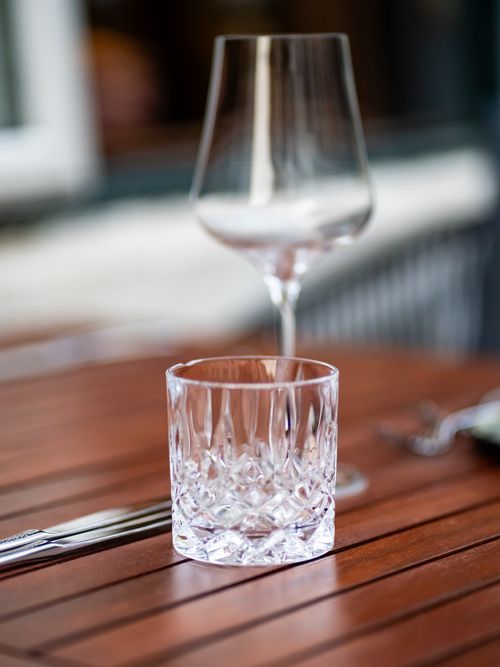 Free Close-up of a crystal glass and wine glass setting on a wooden table outdoors. Stock Photo