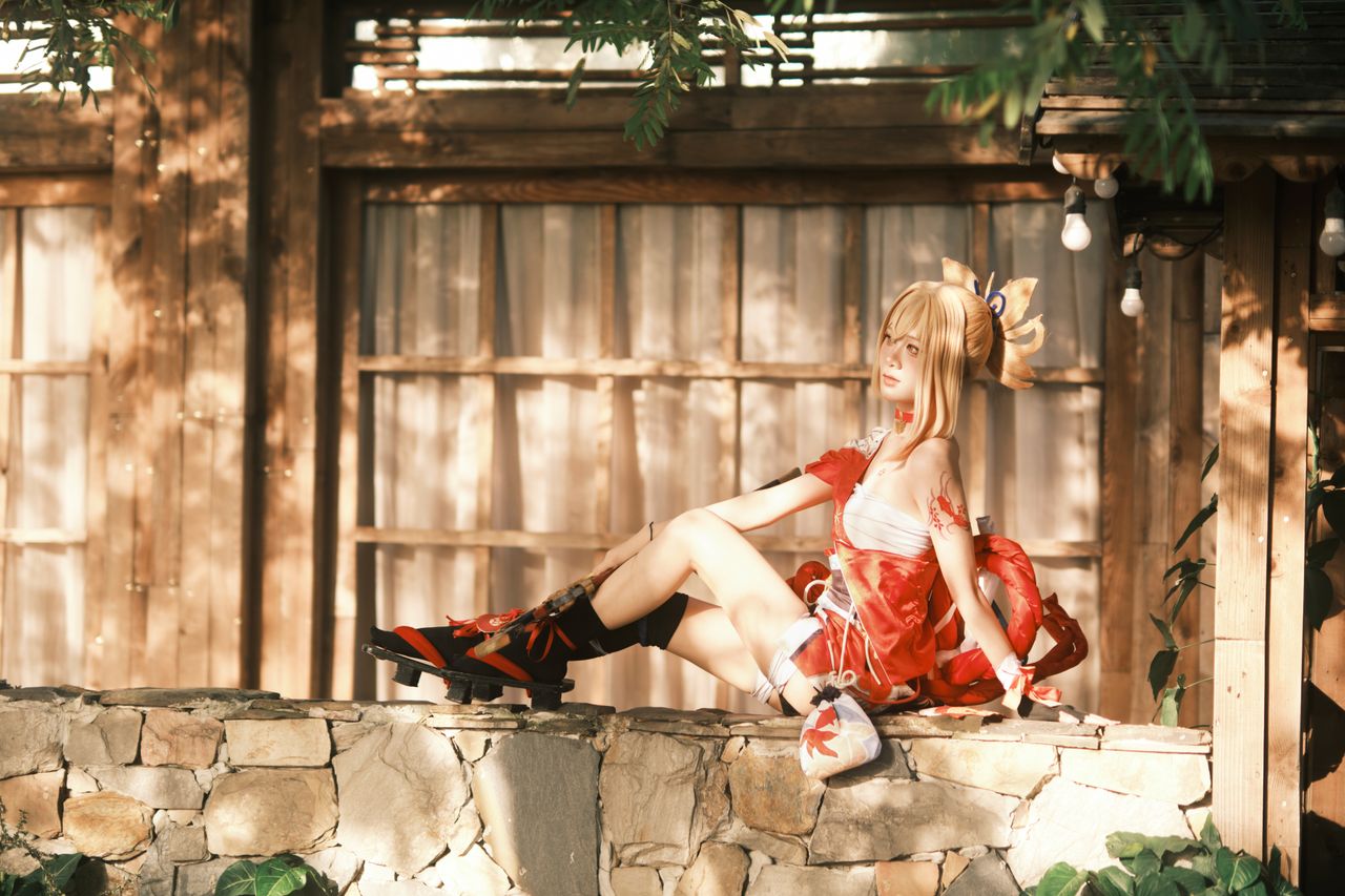a woman in detailed cosplay attire sits elegantly outdoors in warm sun