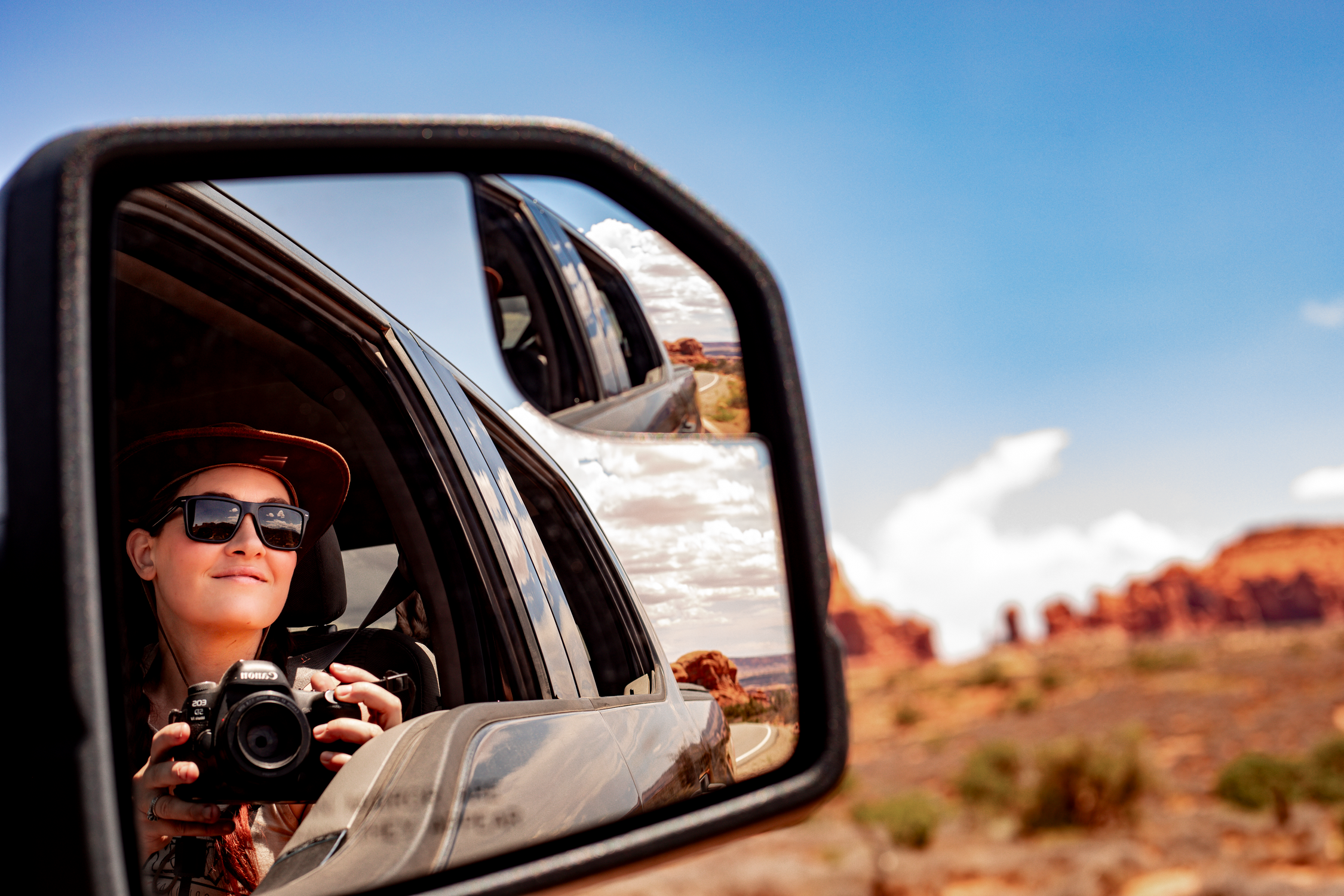 A traveler captures Utah's stunning desert landscape from a car mirror reflection, embodying adventure and exploration.