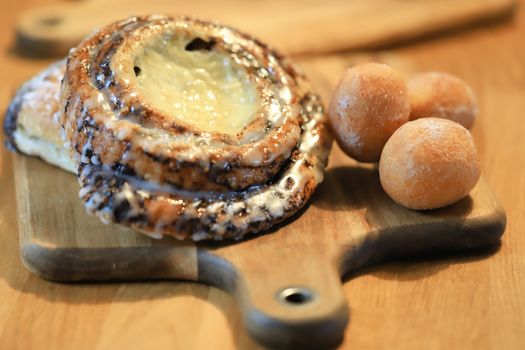 Close-up of delicious pastries including buns and swirls on a wooden serving board.