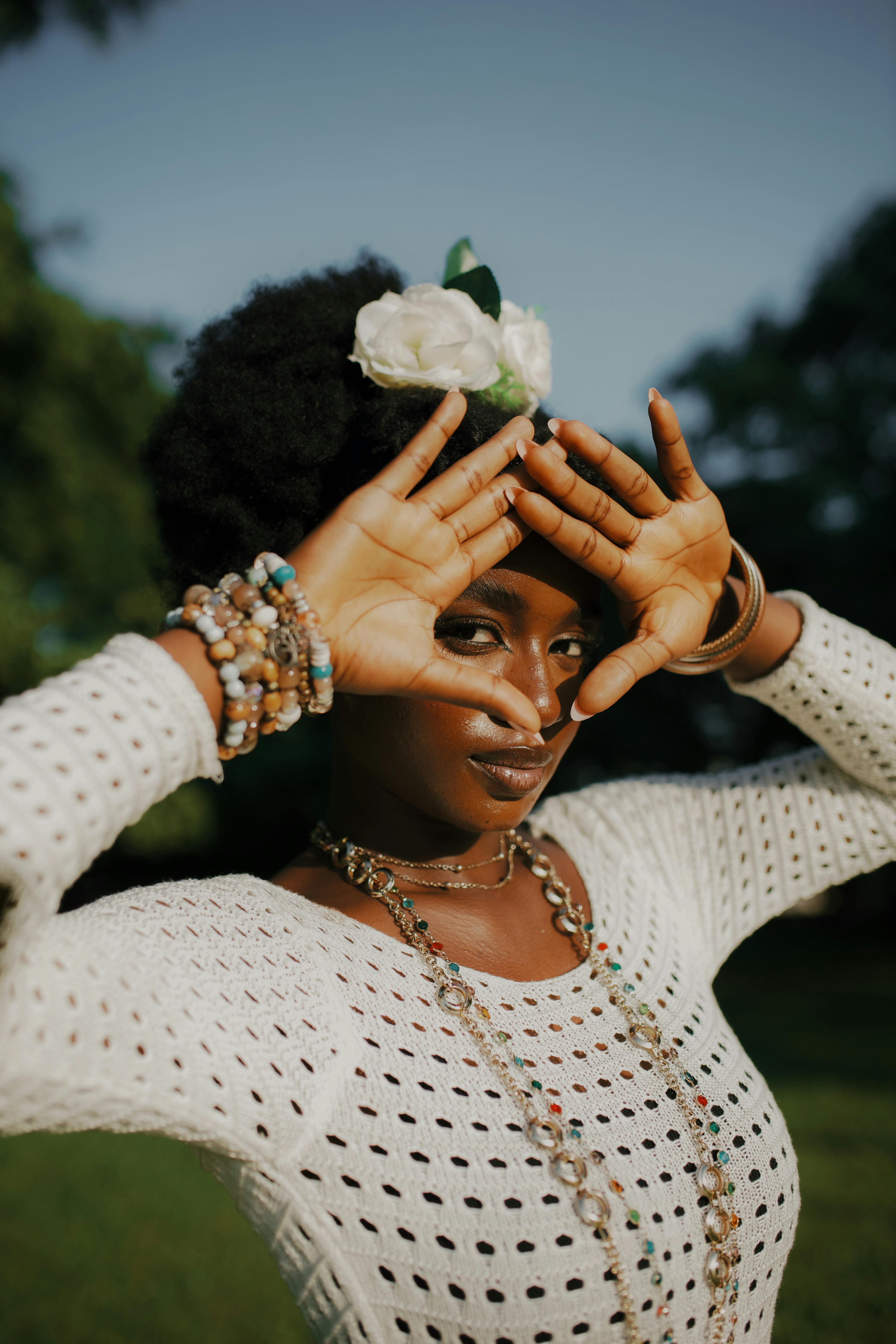Portrait of a stylish African woman outdoors with jewelry and floral headpiece.