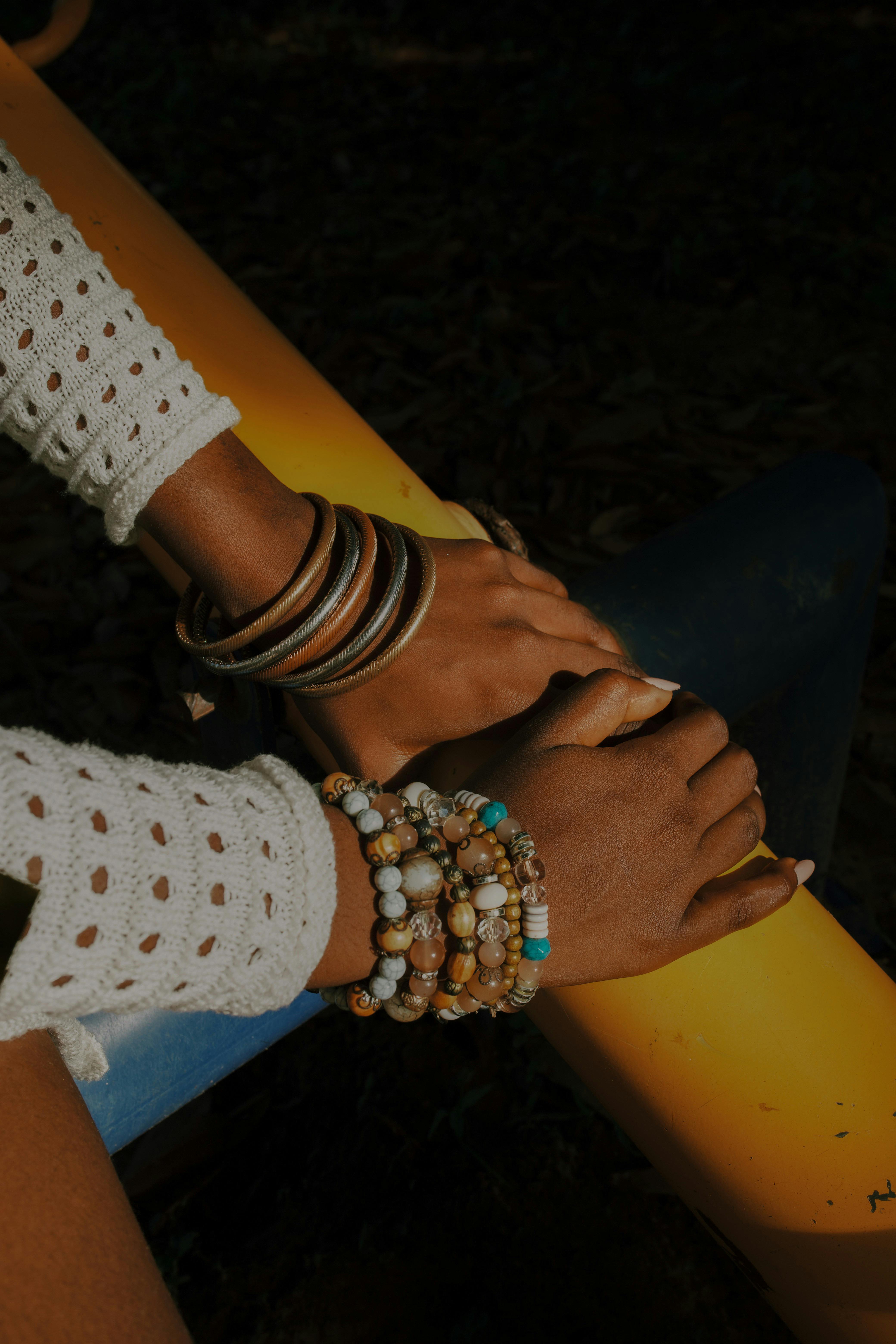 Stylish bohemian jewelry on hands resting on a yellow surface, ideal for fashion themes.