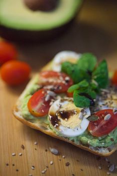 Fresh avocado toast topped with boiled eggs and cherry tomatoes for a healthy breakfast.