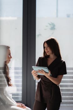 A healthcare professional consults with a patient using a digital tablet in a well-lit clinic.