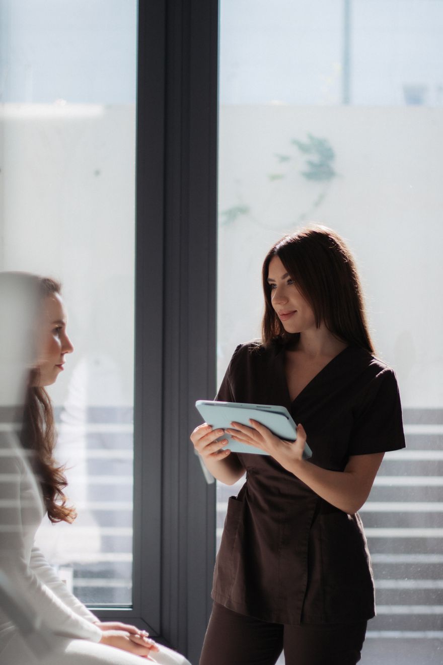 A clinician holding a tablet talks a seated patient through her results. Photo by Anhelina Vasylyk on Pexels