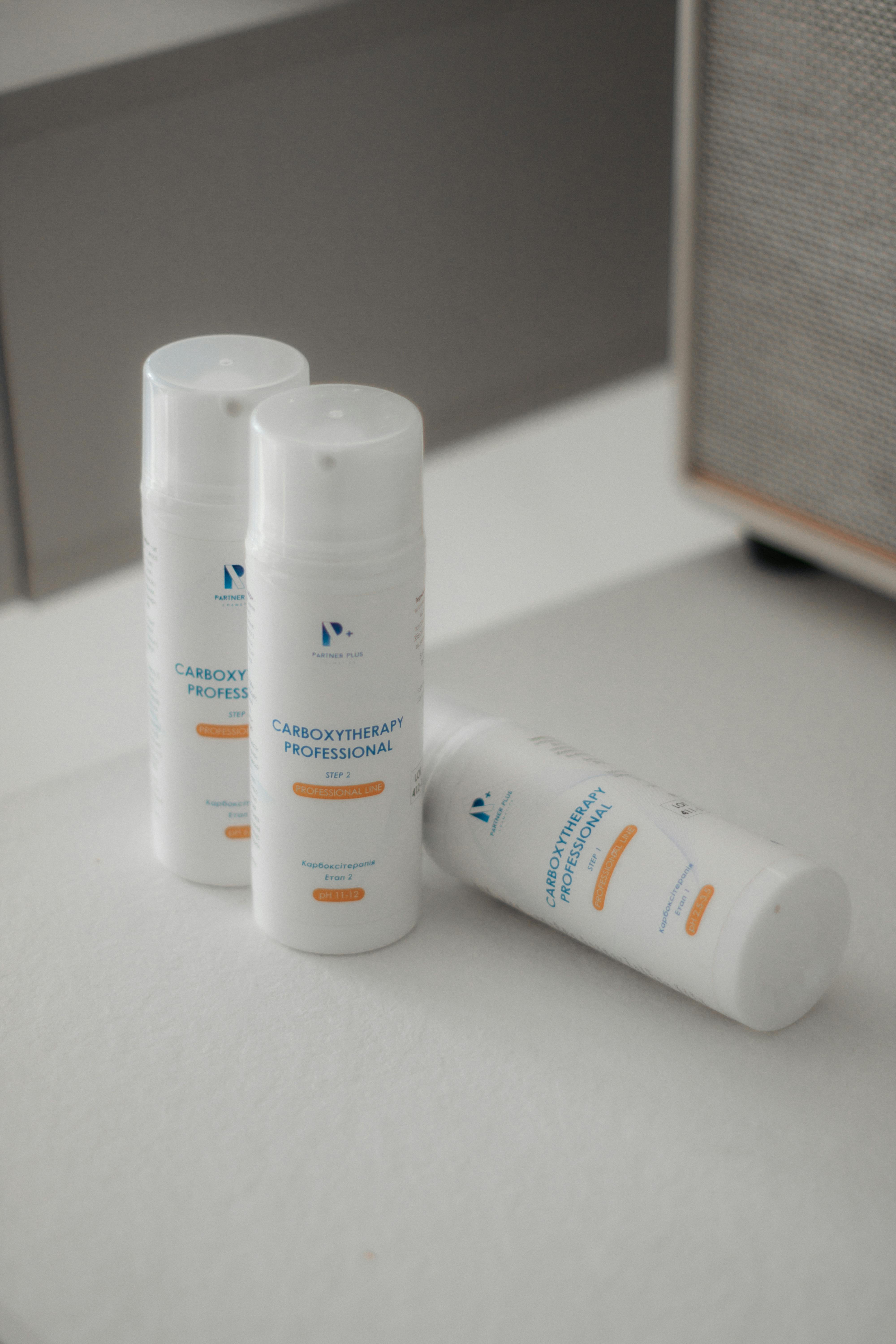 Minimalist display of three skincare bottles indoors, soft lighting.