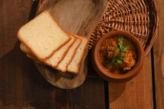 Top view of flavorful chicken curry with bread slices, perfect for a tasty meal.
