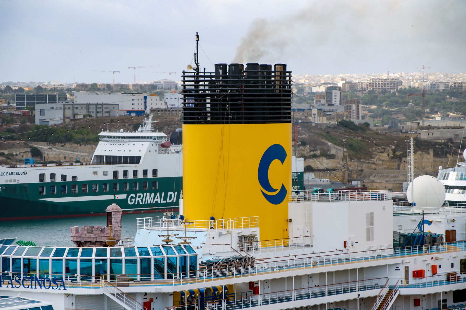 Colorful cruise ships at port in La Valletta, Malta, with industrial background.