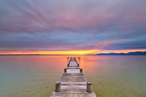 Free Tranquil view of sunset over a wooden pier extending into a calm lake in Bavaria, Germany. Stock Photo