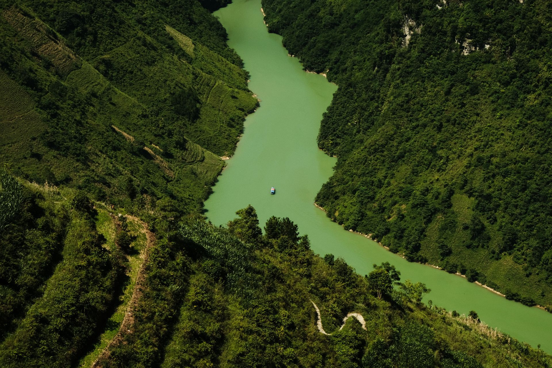 Stunning aerial view of lush green valley with winding river and boat.