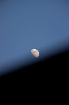 A captivating image of the waxing crescent moon rising against a clear twilight sky, partially obscured by a shadow.