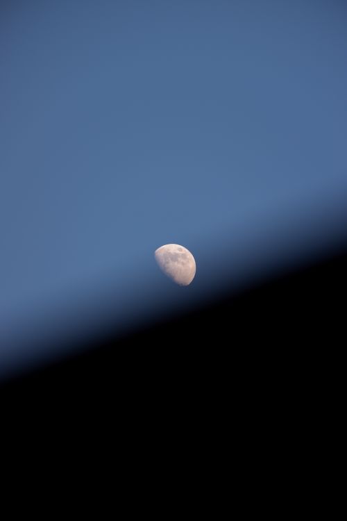 Free A captivating image of the waxing crescent moon rising against a clear twilight sky, partially obscured by a shadow. Stock Photo