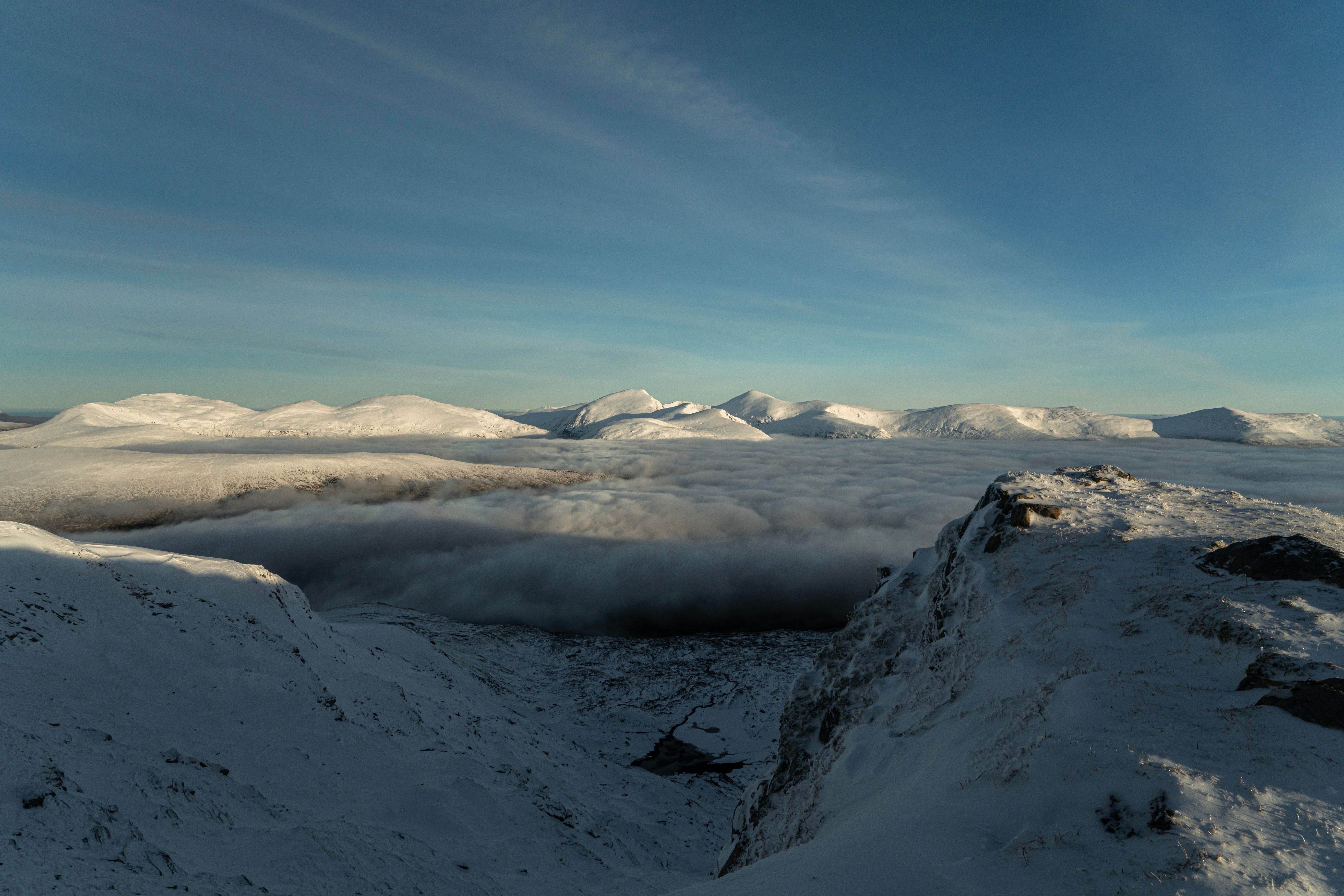 Snow underfoot and a cloud inversion below snow-covered Scottish peaks