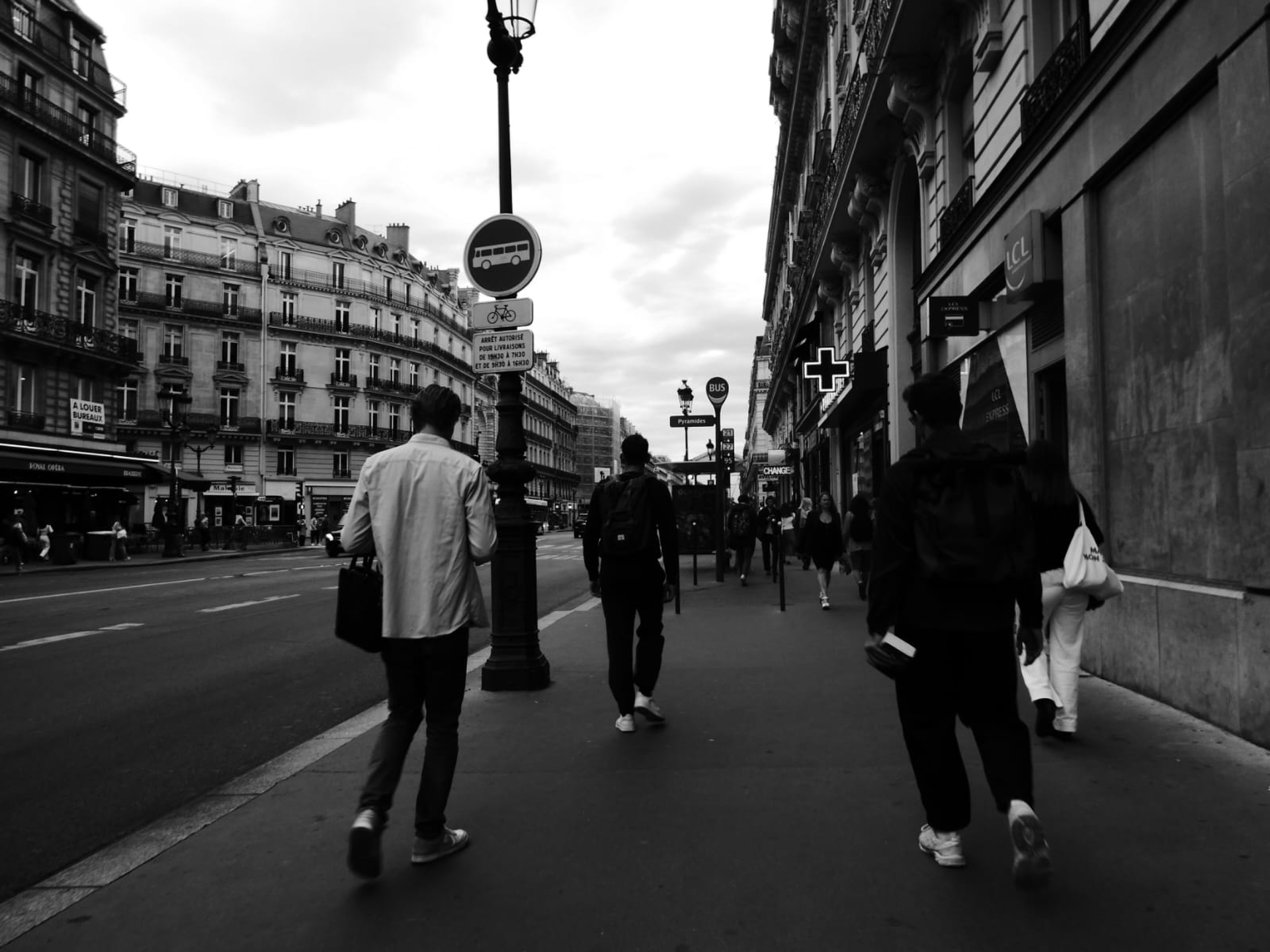 Dramatic black and white view of a busy European city street with pedestrians.