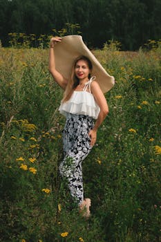 站在野花田里的优雅女子戴着宽边帽，散发着充满活力的夏日气息