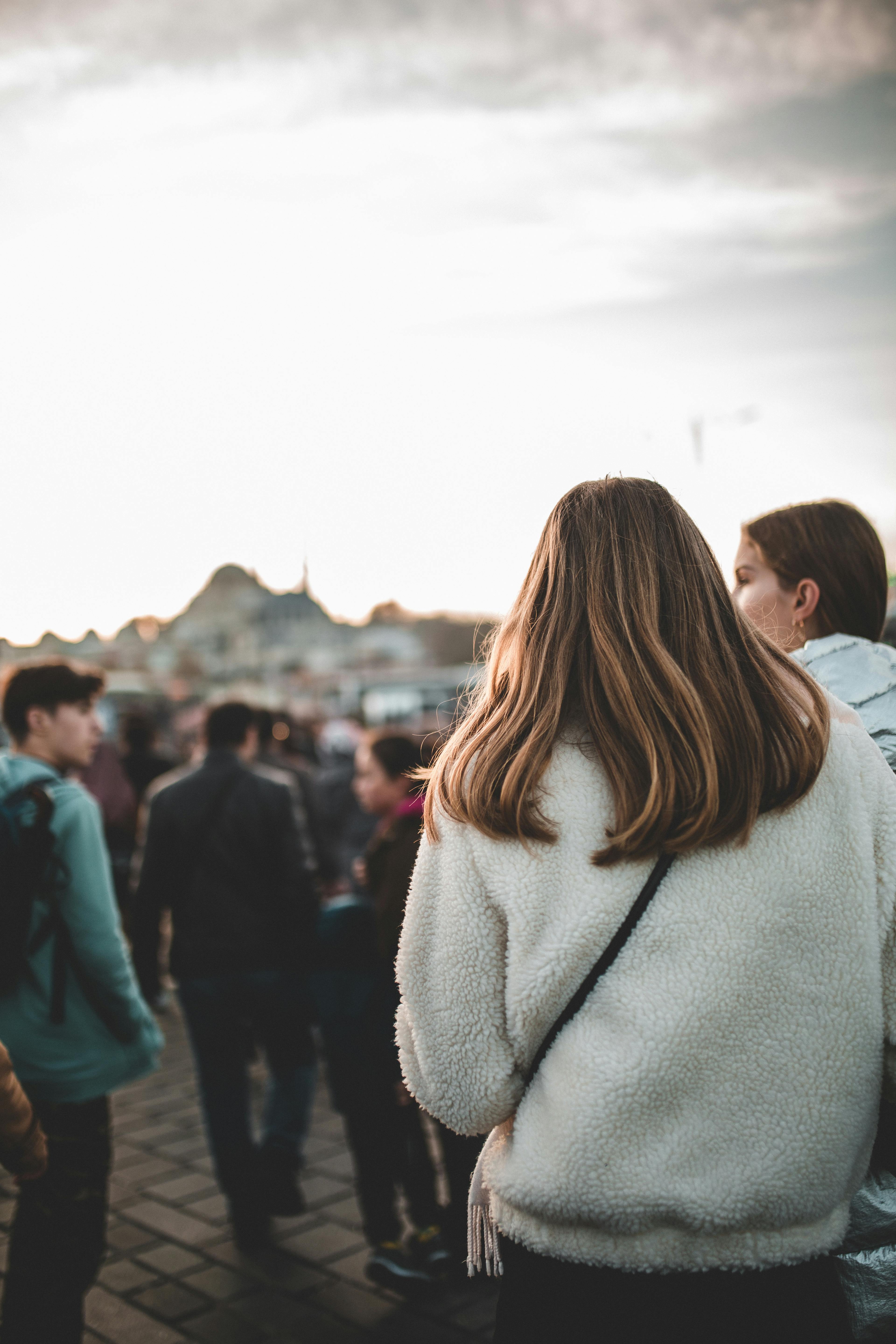 Free Back view of unrecognizable young female traveler in warm clothes walking along touristic street and sightseeing during vacation Stock Photo