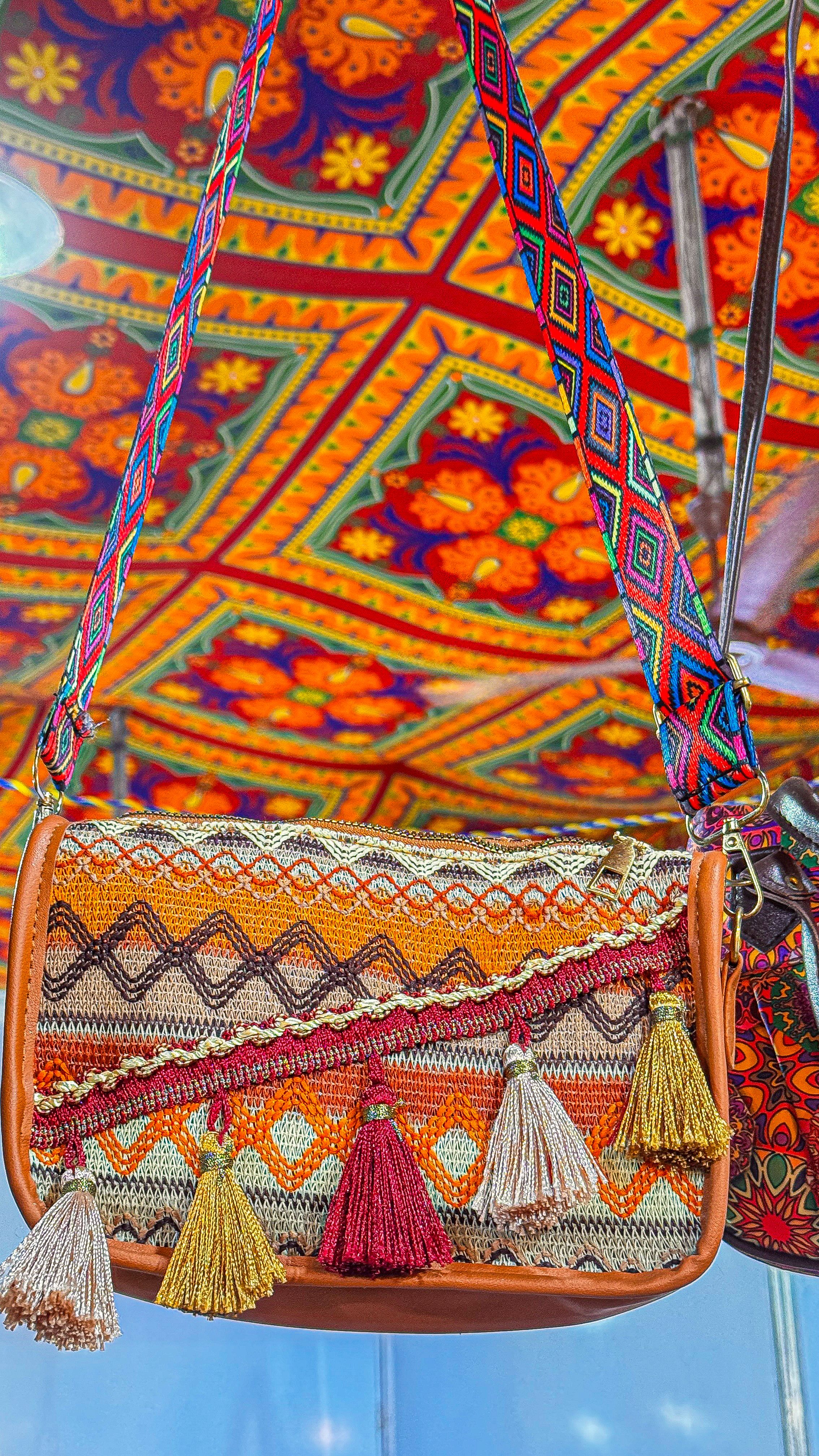 Uma bolsa étnica colorida adornada com padrões vibrantes e franjas sob um toldo tradicional.
