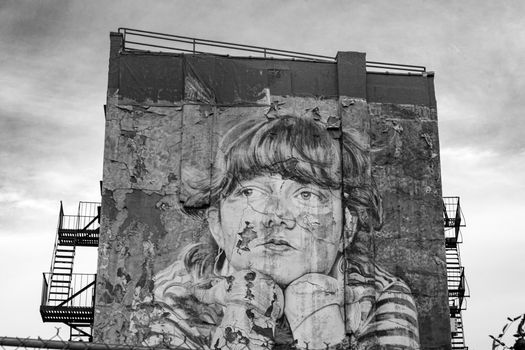 Black and white image of a street art mural on a dilapidated building wall in New York City.