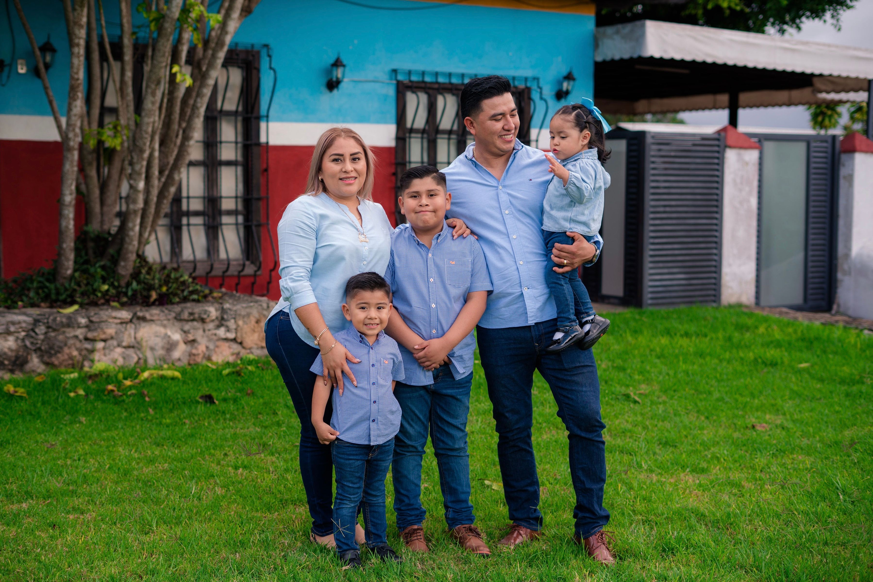 Happy Family Posing Outside a Colorful House · Free Stock Photo